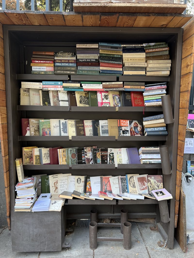 A wooden shelf packed with rows of used books