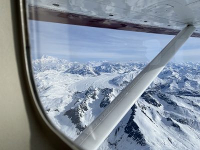 View from a small plane's window over snow-capped Alaska mountains